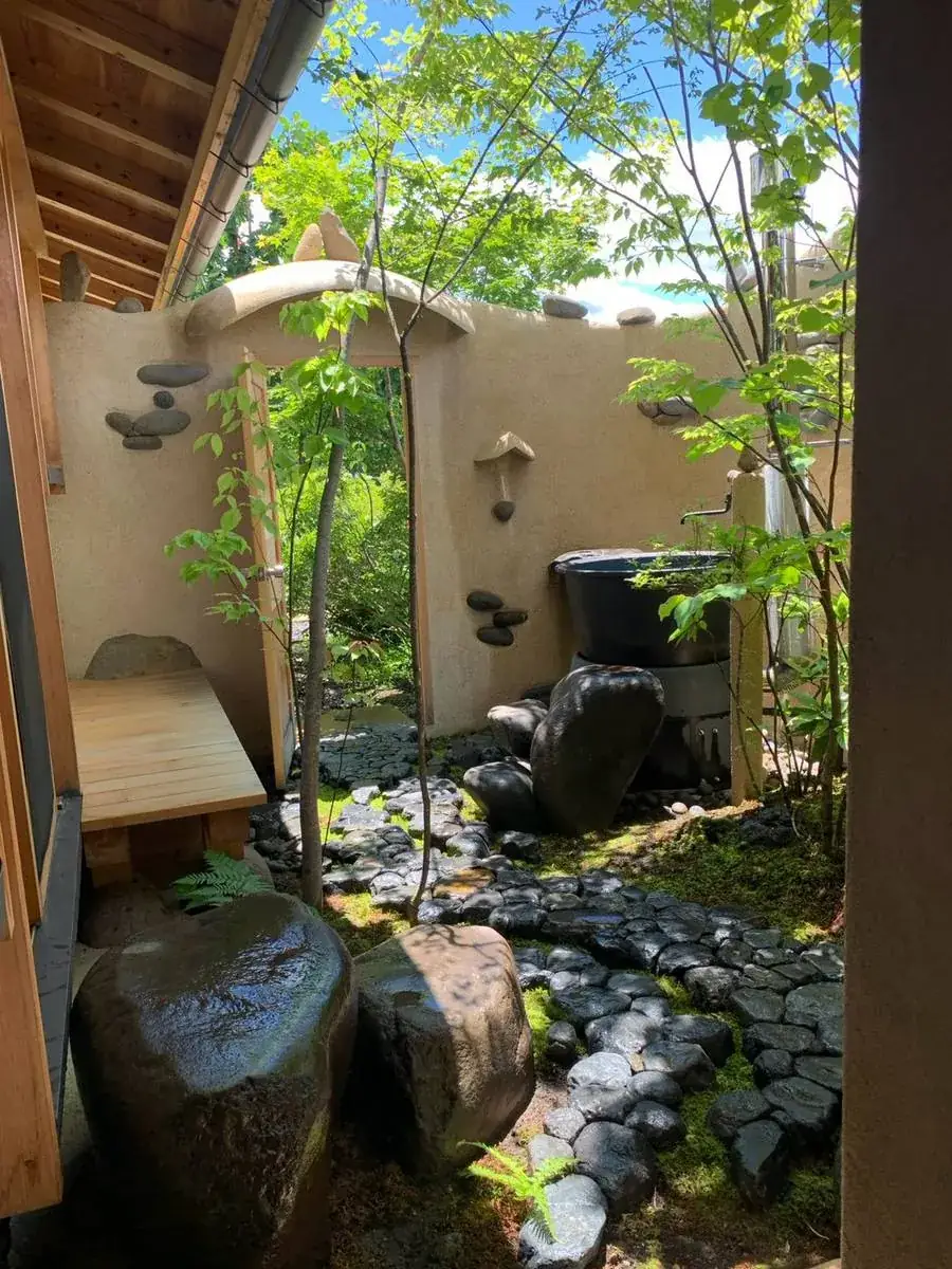 布流久佐の中庭。土壁の門と露天風呂、黒い玉石の小径